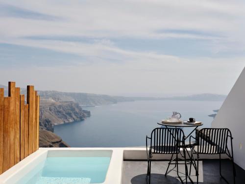 a balcony with a table and chairs and a view of the ocean at Stella Rocca A Mare in Imerovigli
