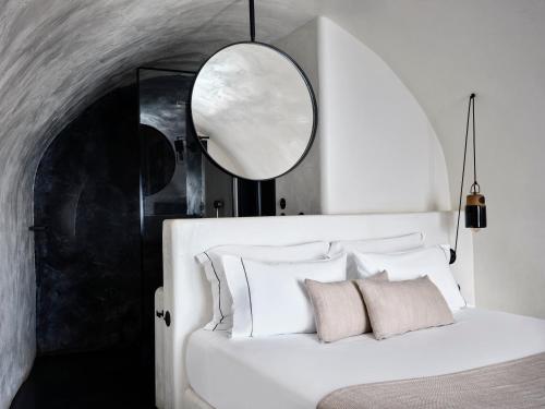 a bedroom with a white bed and a mirror at Stella Rocca A Mare in Imerovigli