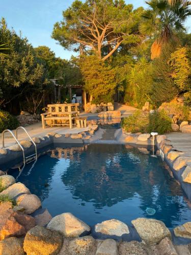 une piscine d'eau avec des rochers dans une cour dans l'établissement Maranatha, Location de Villas pieds dans l'eau, à Porto-Vecchio