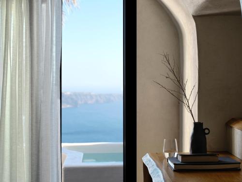 a table with a vase on it next to a window at Stella Rocca A Mare in Imerovigli