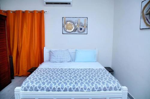 a bed in a bedroom with an orange curtain at Homely stay in the heart of Osu - Studio 2 in Accra