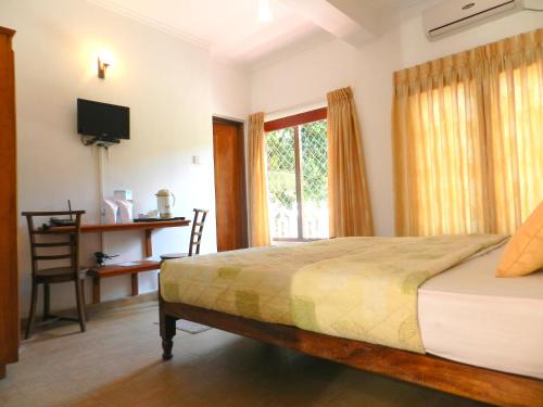 a bedroom with a bed and a tv and a window at Paradise Inn in Kandy