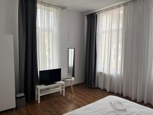 una camera con letto, TV e tende di House of Tourists Garden and More a Bucarest