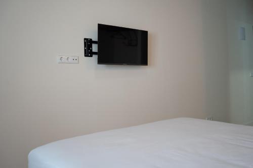 telewizor na białej ścianie nad łóżkiem w obiekcie Estancia dos Olivos w mieście Quesa