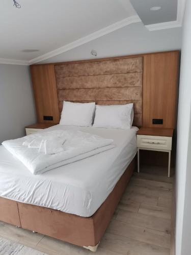 - une chambre avec un grand lit et une tête de lit en bois dans l'établissement O'CHENA AKYUZ PAR in UZUNGÖL, à Çaykara
