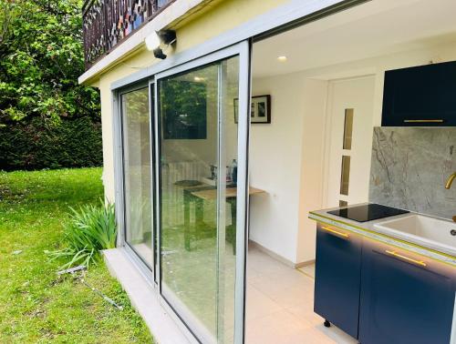 a kitchen with sliding glass doors and a sink at Appart Jardin Lac Casino Enghien Les Bains Paris JO2024 in Soisy-sous-Montmorency