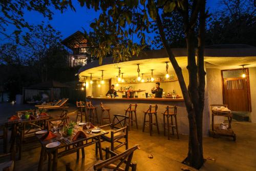 a restaurant with tables and a bar at night at Toyam by Orchid Hotels in Bhor