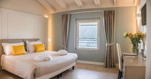 a bedroom with a bed with yellow pillows and a window at Araba Fenice Hotel in Iseo