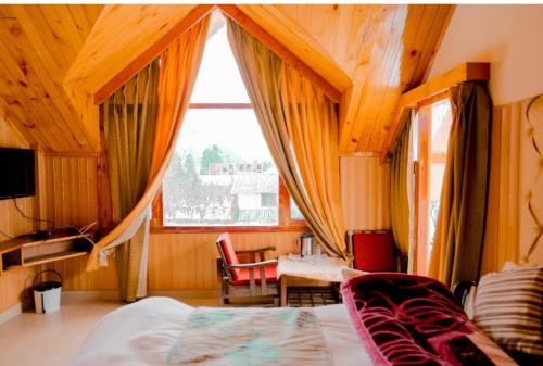 a bedroom with a bed and a table and a window at Himalayan Ecstacy in Manāli