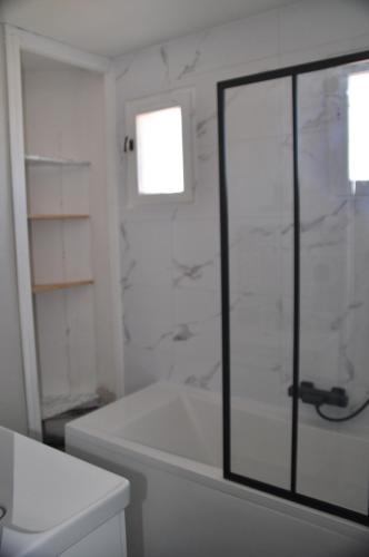 La salle de bains est pourvue d'une baignoire et d'une porte de douche en verre. dans l'établissement Ker Armelle, au Barcarès