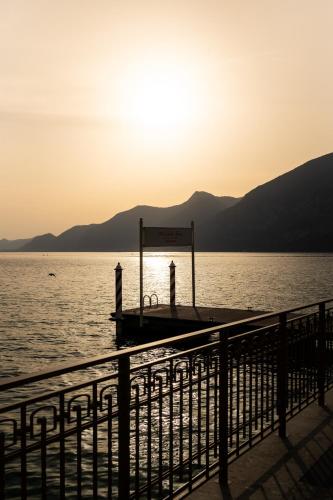 two people standing on a dock in the water at sunset at Araba Fenice Hotel in Iseo