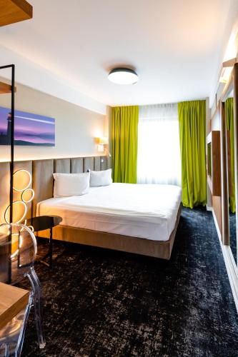 a bedroom with a large bed with green curtains at Business Hotel Conference Center & Spa in Târgu-Mureş