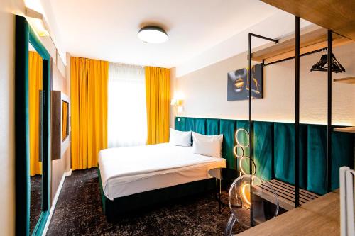 a hotel room with a bed and yellow curtains at Business Hotel Conference Center & Spa in Târgu-Mureş