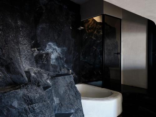 a bathroom with a stone wall and a bath tub at Stella Rocca A Mare in Imerovigli