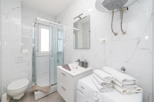 a white bathroom with a toilet sink and a shower at Luxury Apartment Maglica in Makarska