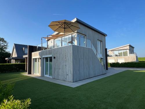 a house with an umbrella on top of a lawn at Villa Maroma Mistral Veerse Meer gratis 4 E-bikes gratis laden EV trampoline in Kamperland