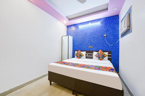 1 dormitorio con 1 cama con pared azul en FabHotel Capital Inn en Ghaziabad