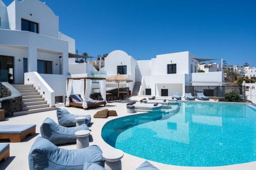 a villa with a swimming pool and white buildings at CUORE SANTO SUITES in Fira