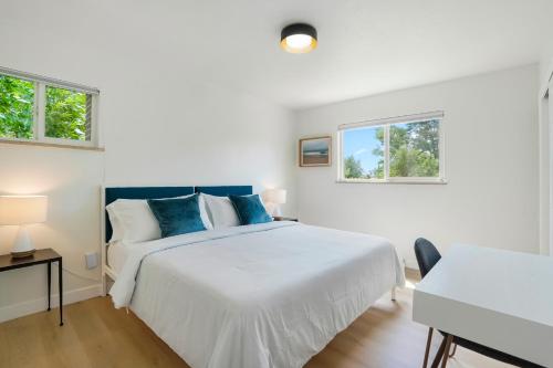 a white bedroom with a large bed and two windows at Large Home, 2 Living Rooms, Great for Family/Pets! in Arvada