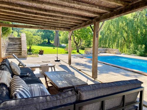 une terrasse avec des canapés, une table et une piscine dans l'établissement Le Petit Chaudenas - Private Pool and Woodland, à Bray