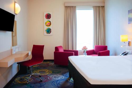 a hotel room with red chairs and a desk at Ibis Styles Dragon Mart Dubai in Dubai