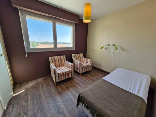 une chambre avec un lit et deux chaises et une fenêtre dans l'établissement MAGNIFIQUE VUE SUR MER T3 rénové, à Saint-Jean-de-Monts