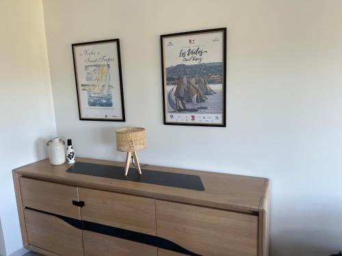 une commode en bois avec deux affiches encadrées sur un mur dans l'établissement T3 Vignes & Terrasse 25 m2 au calme - Vue verdoyante - À 7 min de la plage - Parking Gratuit - La Croix-Valmer, à La Croix-Valmer
