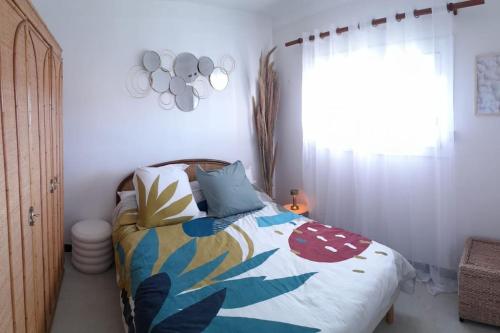 - une chambre avec un lit doté d'une couverture colorée et d'une fenêtre dans l'établissement Face à la Mer, à Port-la-Nouvelle