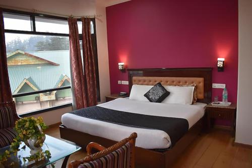 1 dormitorio con cama grande y ventana grande en Hotel Marc Mall Road Shimla - Family Friendly & Parking - A Four Star Luxury Hotel Mountain View, en Shimla
