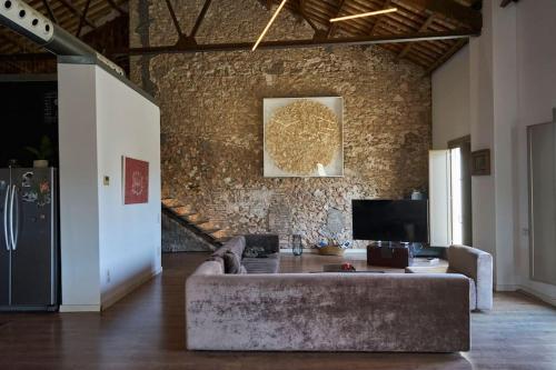 a living room with a couch and a stone wall at molino rehabilitado con gran terraza y piscina in Paterna