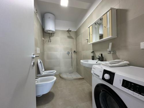a washing machine in a bathroom with a toilet and a sink at Mulaj Hotel in Tirana