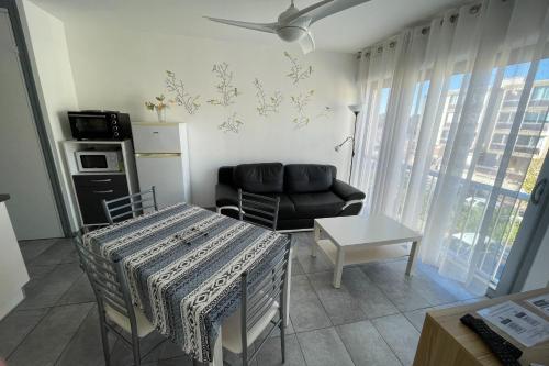 - un salon avec un canapé, une table et une chaise dans l'établissement Balaruc Les Bains Charmant T2, 2 pas des Thermes, à Balaruc-les-Bains