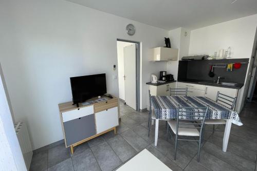 une chambre avec une table et une cuisine avec une télévision dans l'établissement Balaruc Les Bains Charmant T2, 2 pas des Thermes, à Balaruc-les-Bains