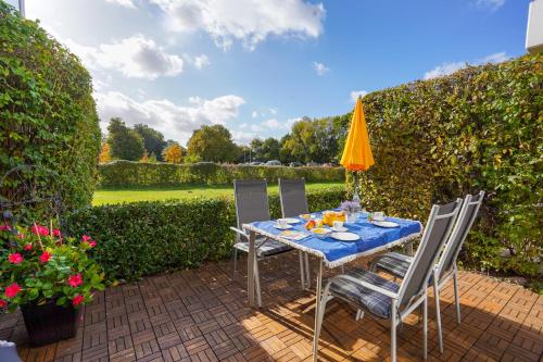 a table with chairs and an umbrella on a patio at Golfresidenz Whg A14 in Grömitz