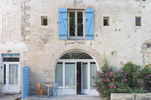 an entrance to a house with blue windows and a table at Gîte Les cyprès de l'ile in Avignon