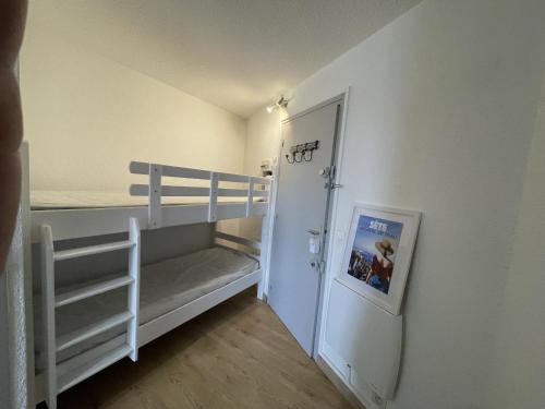 Cette petite chambre comprend des lits superposés et une porte. dans l'établissement Sete, Studio en bord de mer avec terrasse, à Sète