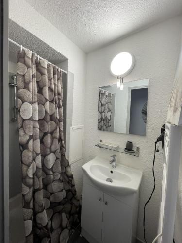 une salle de bain avec un lavabo et un rideau de douche dans l'établissement Sete, Studio en bord de mer avec terrasse, à Sète