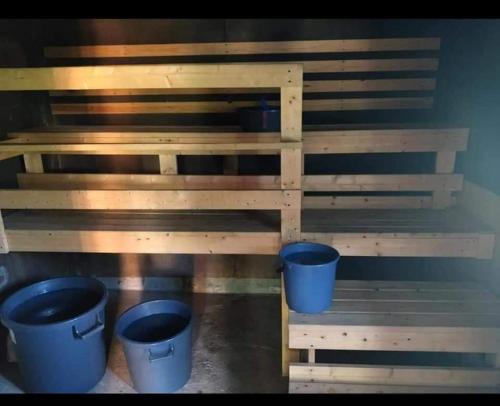 two buckets sitting on a wooden shelf with buckets at Ollinpolun matkakoti in Sulkava