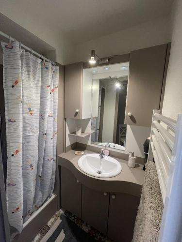 une salle de bain avec un lavabo et un rideau de douche dans l'établissement Sete, Studio en bord de mer, vue imprenable, à Sète