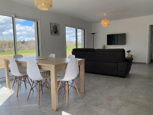 sala de estar con mesa de madera y sillas blancas en Maison neuve, jardin et accès privé à la plage, en Canet-de-Salars