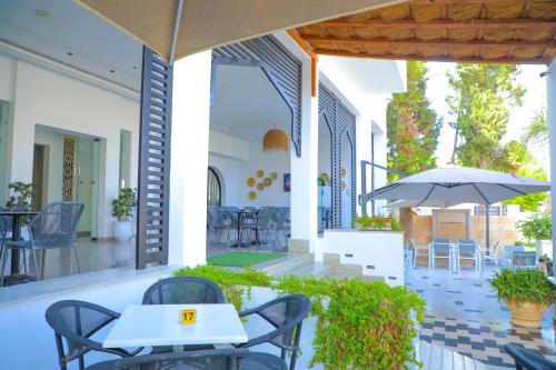 a patio with tables and chairs and an umbrella at نزل قايا Hôtel Gaïa in Nabeul
