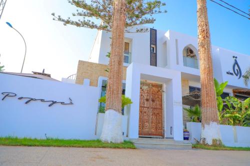 a white house with palm trees in front of it at نزل قايا Hôtel Gaïa in Nabeul