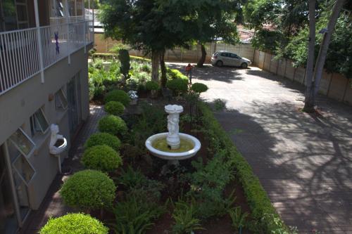 a garden with a fountain in the middle of a building at Purple Olive Guest House in Pretoria