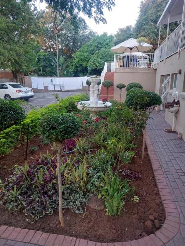 a garden with a fountain in the middle of a yard at Purple Olive Guest House in Pretoria