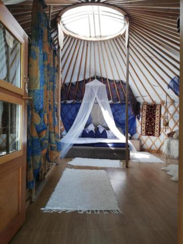 Habitación con cama en una yurta con ventana en Mennyország Jurta Hotel 
