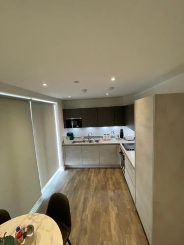 a kitchen with white cabinets and a table with chairs at Upper executive apartment in Dagenham