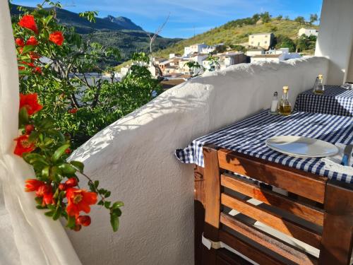 a table on a balcony with red flowers at La Posada Amena in Carcabuey