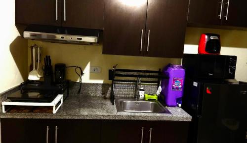 a kitchen counter with a sink and a refrigerator at A Refreshing Condo Unit Near BGC, Ortigas & Makati with NETFLIX and WiFi in Manila