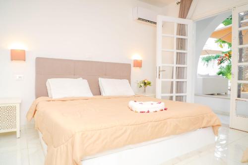 a white bedroom with a large bed with a large window at نزل قايا Hôtel Gaïa in Nabeul