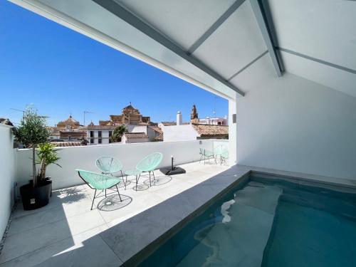 balcón con sillas y piscina en Apartamentos Los Patios de la Judería, en Córdoba